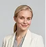 Smiling young woman with blonde hair wearing a light blazer over a blouse.